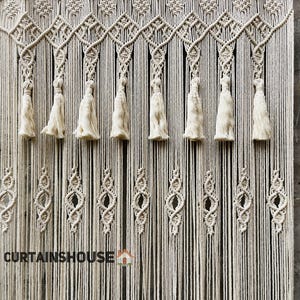Puede incluir: Un tapiz de macram&eacute; color crema con intrincados patrones de nudos, dise&ntilde;os geom&eacute;tricos en forma de diamante y una fila de borlas colgantes. La secci&oacute;n inferior muestra hilos verticales repetidos y el texto CURTAINHOUSE est&aacute; impreso en negro en la parte inferior izquierda.