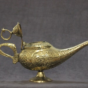 May include: A gold genie lamp with intricate floral and geometric designs. The lamp has a hinged lid and a star-shaped handle.