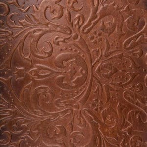 May include: A close-up of a brown leather texture with an embossed floral pattern.