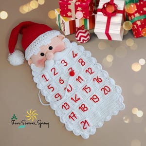 Puede incluir: Un calendario de adviento de ganchillo hecho a mano con la imagen de Papá Noel. El calendario presenta un gorro rojo de Papá Noel, una barba blanca con números rojos y una cara sonriente. El texto "Four.Seasons_Spring" es visible.