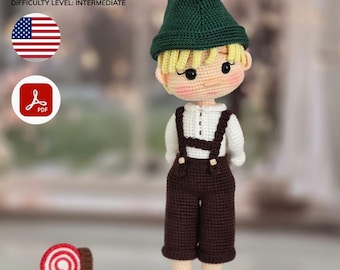 Puede incluir: Muñeco de ganchillo de un niño pequeño con gorro verde, camisa blanca y peto marrón. El muñeco tiene pelo rubio y mejillas rosadas. Un pequeño caramelo de ganchillo está al lado del muñeco. Nivel de dificultad: intermedio.