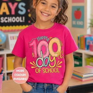 May include: A vibrant pink t-shirt featuring the text "Happy 100th Day of School" in various colours. The shirt is worn by a young person. A button on the shirt says "More Colours Available".