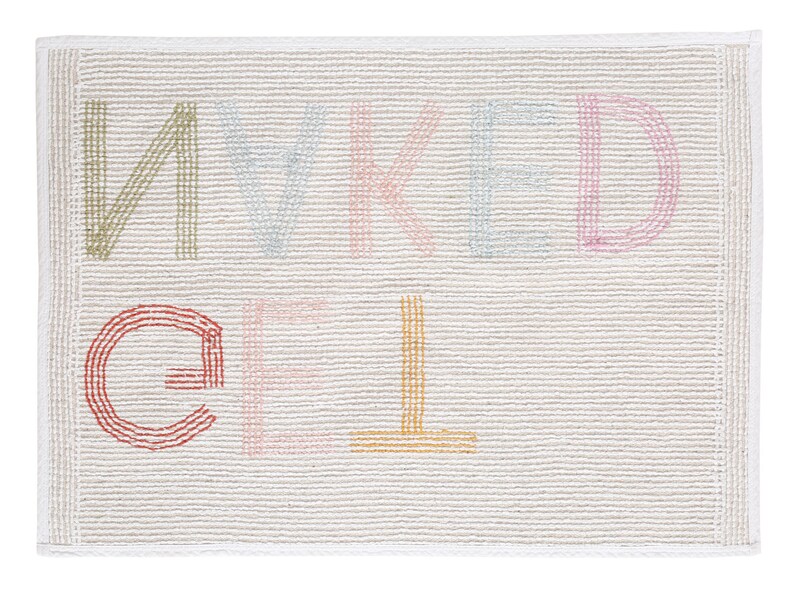May include: A white bath mat with the words "naked" and "gel" embroidered in colorful thread.