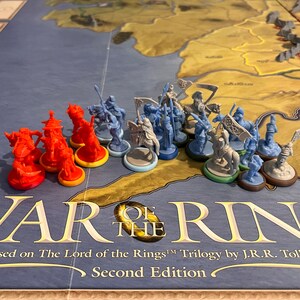Puede incluir: Un tablero de juego con figuras en miniatura y bases. El tablero muestra un mapa de la Tierra Media. El juego se llama "War of the Ring" y est&aacute; basado en la trilog&iacute;a de El Se&ntilde;or de los Anillos de J.R.R. Tolkien. El juego est&aacute; en su segunda edici&oacute;n.