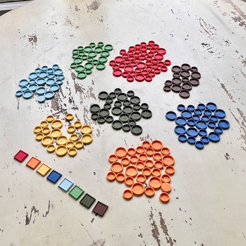 Puede incluir: Un conjunto de piezas de juego de colores en varias formas, incluyendo c&iacute;rculos, cuadrados y rect&aacute;ngulos. Las piezas est&aacute;n dispuestas en un patr&oacute;n sobre una superficie de madera blanca.