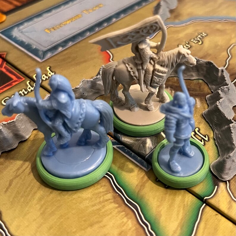 Puede incluir: Tres figuras en miniatura de jinetes a caballo, pintadas de color azul claro. Las figuras est&aacute;n sobre bases circulares con un anillo exterior verde y un anillo interior azul claro. Las figuras son de un juego de mesa de fantas&iacute;a.