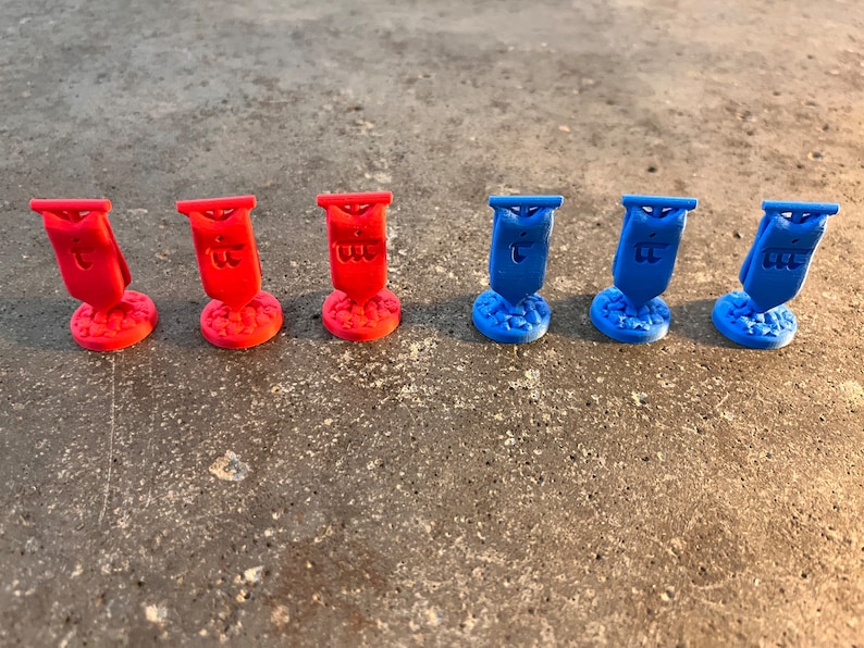 K&ouml;nnte beinhalten: Sechs Miniaturflaggen, drei rote und drei blaue, mit einem Symbol auf jeder Flagge. Die Flaggen befinden sich auf einer grauen Oberfl&auml;che.