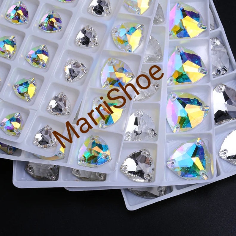 May include: A collection of iridescent, triangular rhinestones in a white plastic organizer. The rhinestones have a multifaceted design, reflecting a spectrum of colors. The text "MarriShoe" is visible in the image.