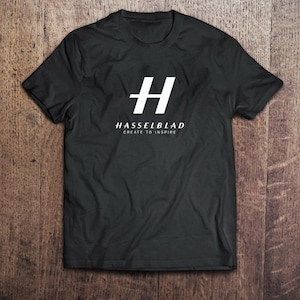 Könnte beinhalten: Schwarzes T-Shirt mit einem weißen "H"-Logo und dem Text "Hasselblad Create to Inspire".
