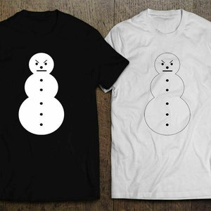 May include: Two t-shirts with a simple black and white graphic of an angry snowman. The snowman has a frown and three buttons. One shirt is black with a white snowman, and the other is white with a black snowman.