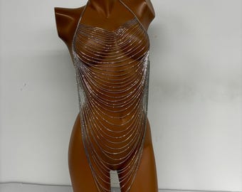 May include: A silver body chain made of multiple rows of small, linked beads. The chain is draped over a mannequin, creating a layered effect.