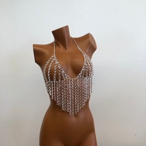 Op de afbeelding: Een body chain van kristallen kralen met een halterhalslijn en een franje-ontwerp. De ketting is gemaakt van heldere kristallen en is geregen op een zilveren ketting.