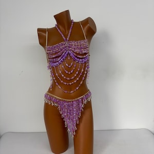 May include: A purple beaded lingerie set with a halter top and a matching bottom. The set is made with small, iridescent beads and features a delicate, feminine design.