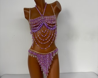 May include: A purple beaded lingerie set with a halter top and a matching bottom. The set is made with small, iridescent beads and features a delicate, feminine design.