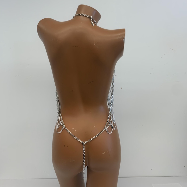 May include: Silver body chain with multiple layers of delicate chains and a long chain that hangs down the back.
