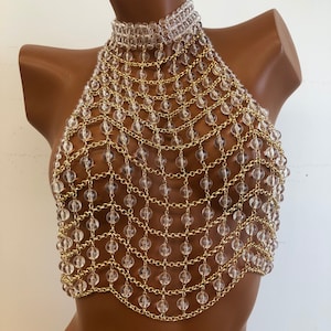 May include: A gold chain body jewelry piece with clear plastic beads. The chain is layered and forms a mesh pattern.