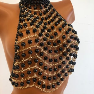 May include: A black and gold beaded halter top with a chain link design. The top is made of small black beads and gold chain links.