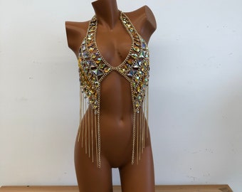 May include: A gold chain body jewelry with iridescent rhinestones and dangling chains. The jewelry is worn on a mannequin.