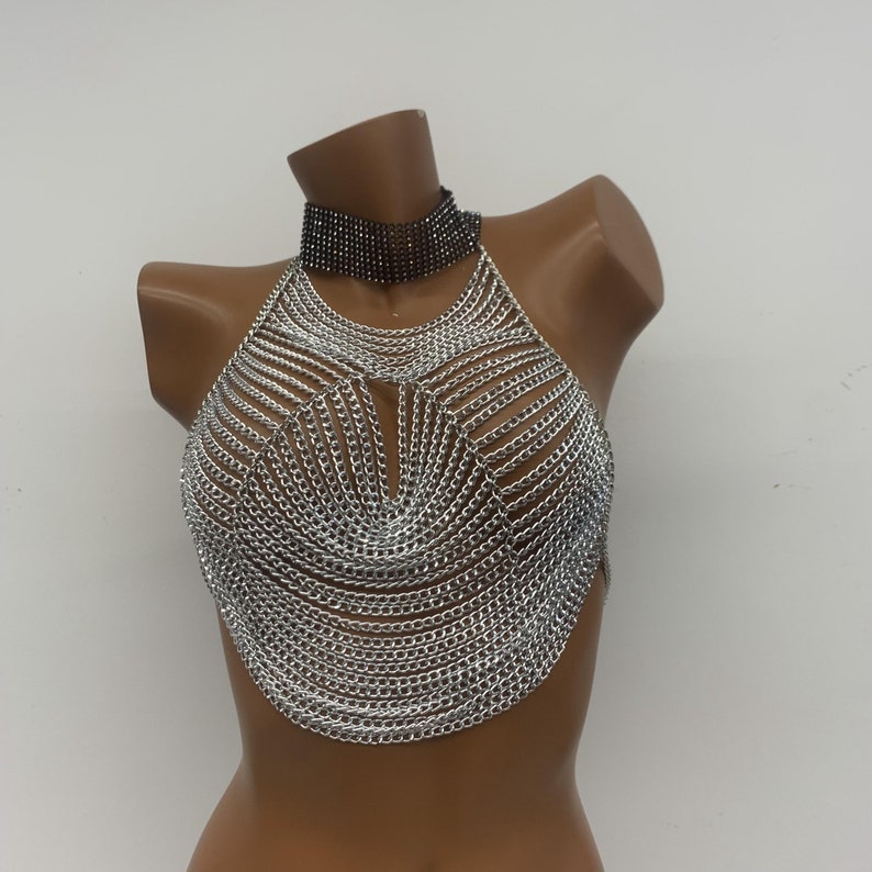 May include: Silver chainmail halter top with a black rhinestone choker.