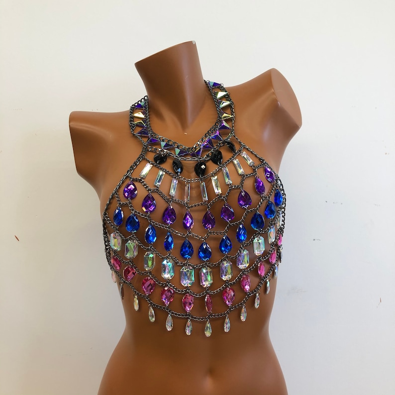 K&ouml;nnte beinhalten: Ein silberner Ketten-K&ouml;rper-Schmuck mit schillernden rosa, blauen und violetten Edelsteinen. Die Kette ist aus Metall und hat einen Halterneck-Ausschnitt.
