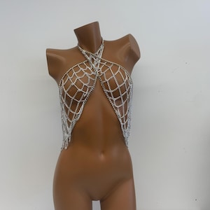 May include: Silver chainmail top with a criss-cross design. The top is made of small, linked chains that create a delicate and intricate pattern.