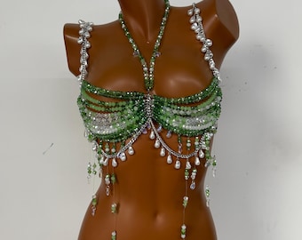 May include: A green beaded top with silver chain accents and dangling pearl-like beads. The top is displayed on a mannequin and features a halter neck design with multiple rows of green beads and a central beaded design.