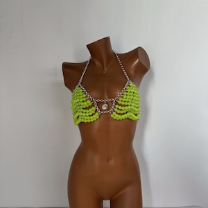 May include: A lime green beaded chain bra with a silver chain and a rhinestone accent.
