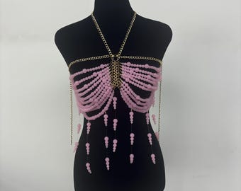 Op de afbeelding: Een roze kralen body chain met gouden kettingaccenten. De ketting is gemaakt van kleine roze kralen en heeft een delicate, vrouwelijke uitstraling.