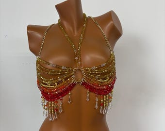 May include: A beaded bra top with a gradient of red, orange, and gold beads. The bra top has a chain-like design and features clear crystal accents.
