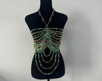 May include: A beaded halter top with a geometric design. The top is made of green, brown, and clear beads. The beads are strung together in a pattern that resembles a rib cage.