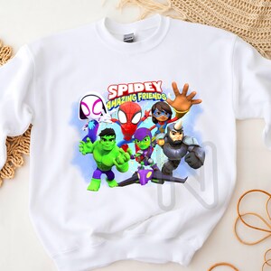 May include: White sweatshirt with a colorful graphic print of Spider-Man and his friends. The text "SPIDEY AMAZING FRIENDS" is printed above the characters.
