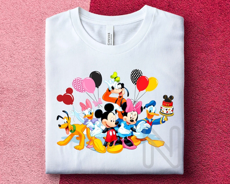 May include: White t-shirt with a colorful graphic of Mickey Mouse, Minnie Mouse, Donald Duck, Goofy, and Pluto celebrating with balloons and a birthday cake.