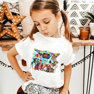 May include: White t-shirt with a colorful graphic of characters from the movie "Coco" and the text "ABC Coco The Day of the Dead".