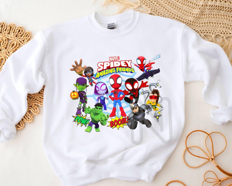 Peut inclure: Sweat-shirt blanc avec un imprim&eacute; graphique color&eacute; de Spider-Man et ses amis. L'impression comprend le texte "Marvel Spidey Amazing Friends" et met en sc&egrave;ne des personnages comme Green Goblin, Spider-Gwen et Doc Ock.
