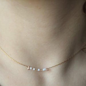 Può includere: Una delicata collana a catena dorata con una piccola fila di perline bianche e dorate.