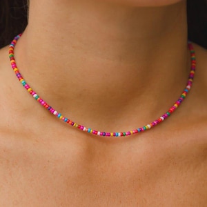 Peut inclure: Un collier de perles colorées composé de petites perles multicolores. Le collier est orné de perles roses, jaunes, vertes, bleues et blanches, créant un accessoire joyeux.