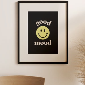 Może przedstawiać: Czarny plakat w ramie z ż&oacute;łtą buźką i tekstem "good mood" w jasnor&oacute;żowym kolorze.