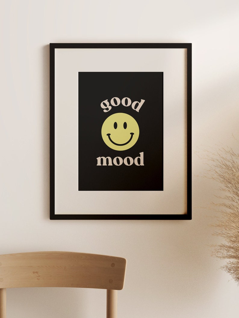 Może przedstawiać: Czarny plakat w ramie z ż&oacute;łtą buźką i tekstem "good mood" w jasnor&oacute;żowym kolorze.