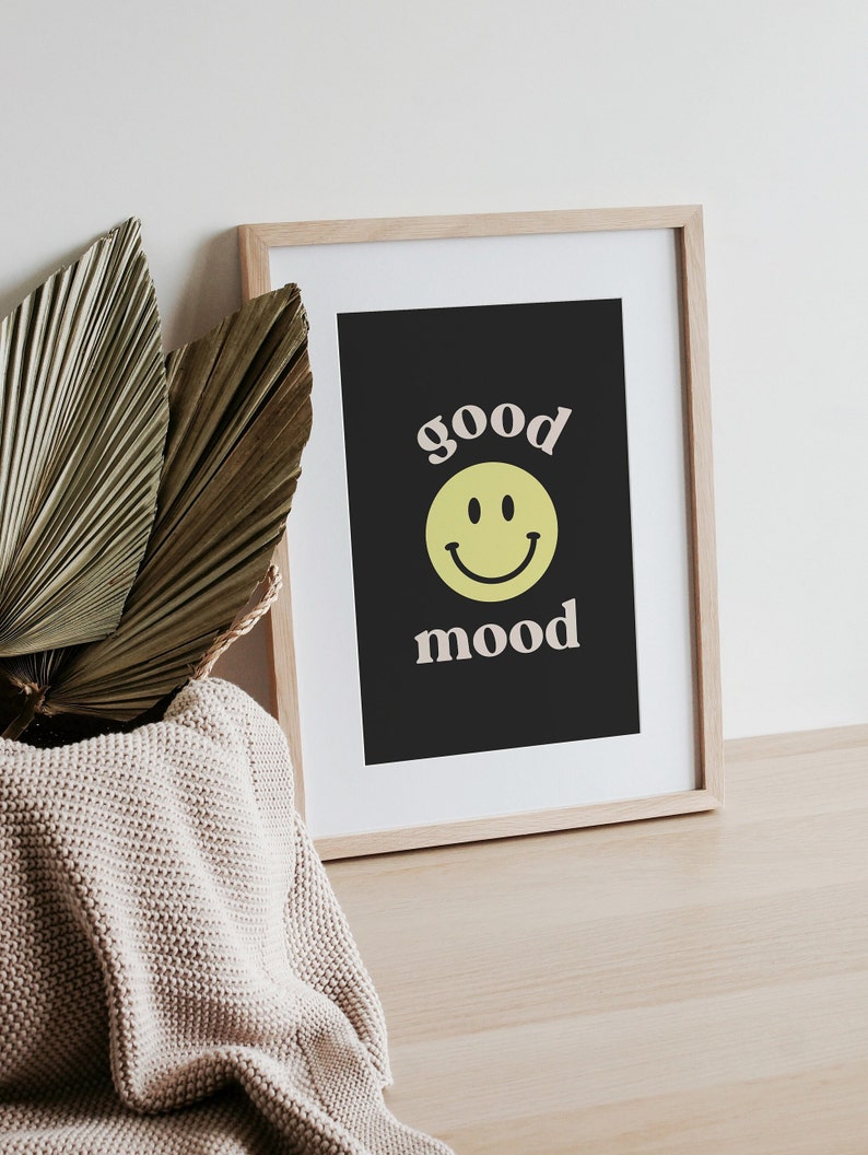 Może przedstawiać: Wydruk w ramie z czarnym tłem i białym tekstem, kt&oacute;ry brzmi "good mood" z ż&oacute;łtą buźką między słowami.