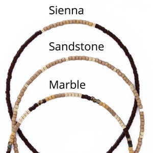 May include: Three beaded necklaces in shades of brown, beige, and gold. The top necklace is dark brown, labeled "Sienna." The middle necklace is beige, labeled "Sandstone." The bottom necklace is a mix of colors, labeled "Marble."