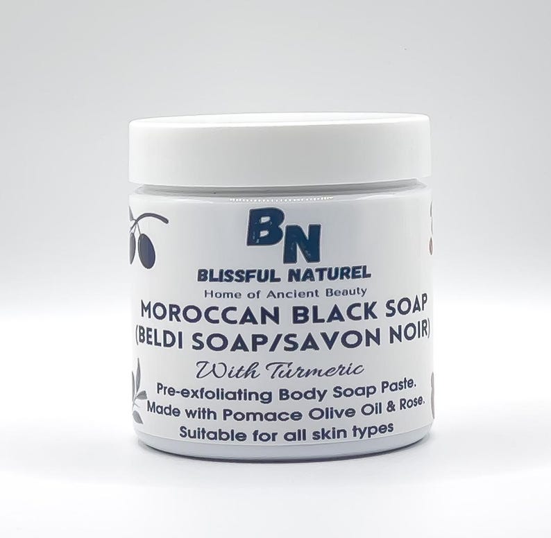 May include: A white jar with a white lid, labeled "MOROCCAN BLACK SOAP" with the text "BLISSFUL NATUREL" and "Home of Ancient Beauty". The jar also says "With Turmeric" and "Pre-exfoliating Body Soap Paste."