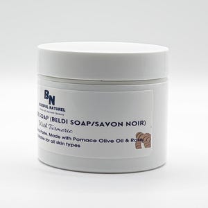 May include: A white jar of Beldi Soap with turmeric. The label reads "BLISSFUL NATUREL" and "SOAP (BELDI SOAP/SAVON NOIR)". The text also mentions the soap is made with pomace olive oil and rose, suitable for all skin types.