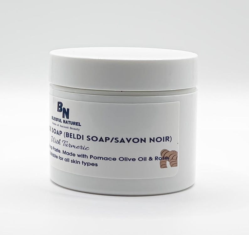 May include: A white jar of Beldi Soap with turmeric. The label reads "BLISSFUL NATUREL" and "SOAP (BELDI SOAP/SAVON NOIR)". The text also mentions the soap is made with pomace olive oil and rose, suitable for all skin types.