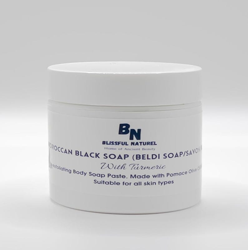 May include: A white jar of Moroccan black soap with turmeric. The label reads "BLISSFUL NATUREL" and "Moroccan Black Soap (Beldi Soap/Savon) With Turmeric". The jar is a body soap paste made with pomace olive oil, suitable for all skin types.