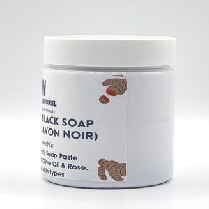 May include: A white jar with a white lid, labeled "BLACK SOAP (SAVON NOIR)". The label includes text and illustrations of turmeric. The product is a body soap paste with olive oil and rose, suitable for all skin types.