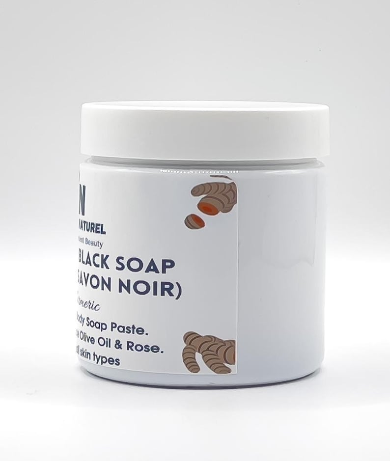 May include: A white jar with a white lid, labeled "BLACK SOAP (SAVON NOIR)". The label includes text and illustrations of turmeric. The product is a body soap paste with olive oil and rose, suitable for all skin types.