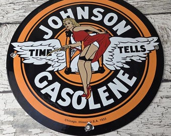 May include: Round metal sign with a black and orange border featuring the text "JOHNSON GASOLENE" and a pin-up girl illustration. The sign also includes the text "TIME TELLS" and "Chicago, Illinois U.S.A. 1933".