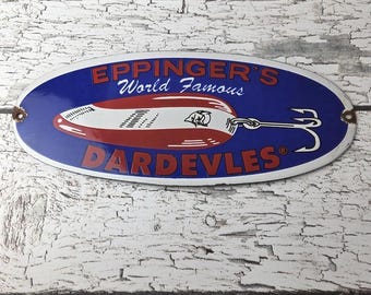 May include: Oval metal sign with a blue background and the words "EPPINGER'S World Famous DARDEVLES" in red. The sign features a red and white fishing lure design with a hook.