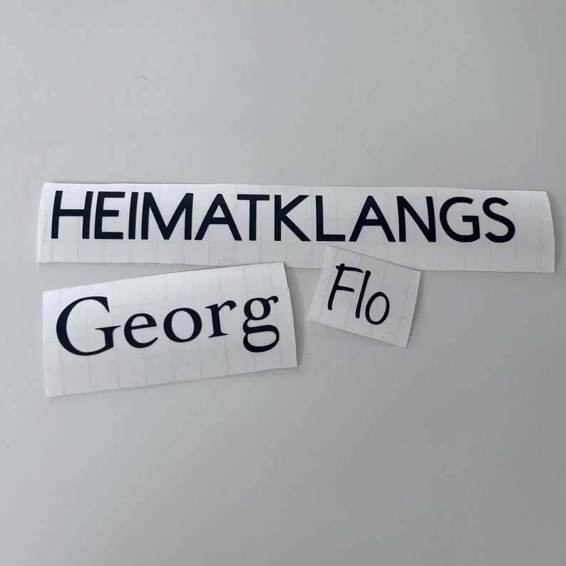 May include: Three white paper labels with black text. The top label reads "HEIMATKLANGS". The middle label reads "Georg". The bottom label reads "Flo".