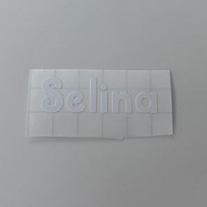 May include: White vinyl sticker with the name "Selina" in a cursive font.
